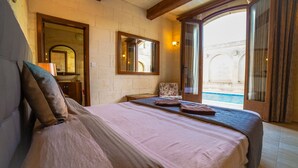 A bedroom with a bed, a nightstand, a mirror, and a view of a pool.