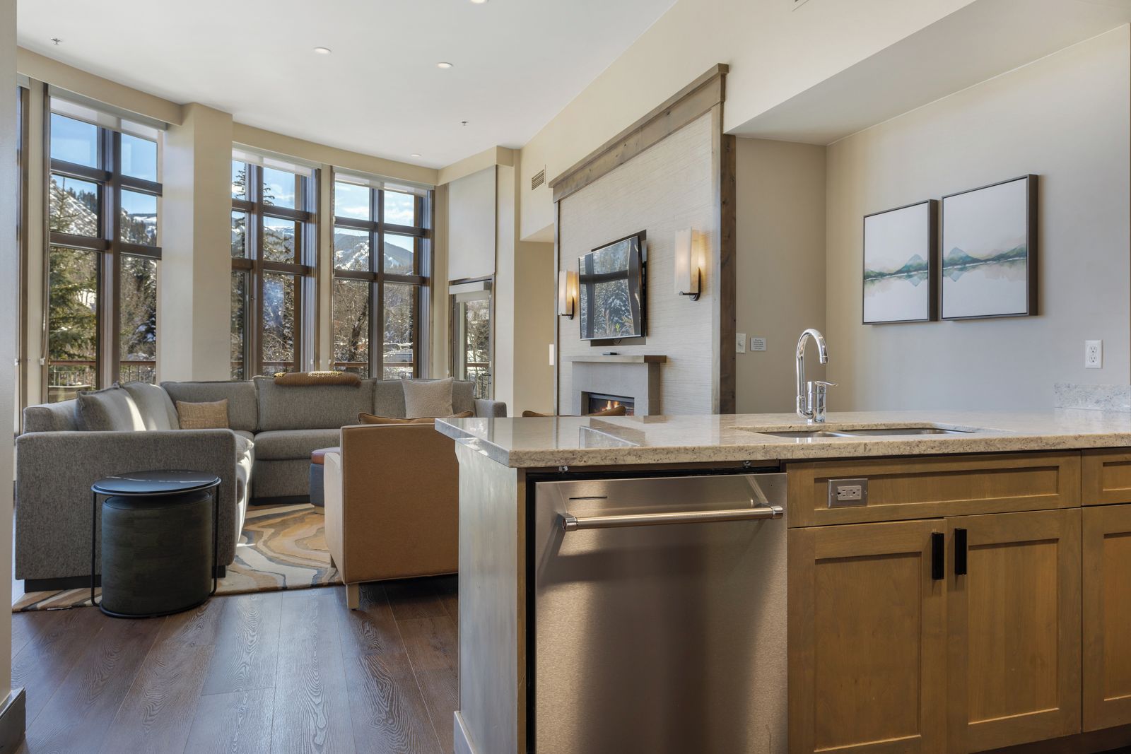 A modern kitchen with a built-in dishwasher, a large window, and a cozy seating area with a fireplace.