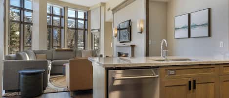 A modern kitchen with a built-in dishwasher, a large window, and a cozy seating area with a fireplace.