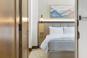 Une chambre d’hôtel avec un lit, une table de chevet, une lampe et un tableau au mur.