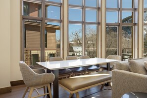 Un comedor con una mesa y sillas, ventanas amplias y vistas al exterior.