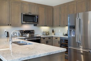 A modern kitchen with stainless steel appliances, granite countertops, and wooden cabinets. - Charlie Rentz: Remodeled, Sleeps 12, Huge Wraparound Deck, Gondola, Views + Resort Amenities (Avon)