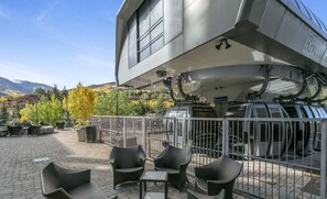 Un bâtiment moderne doté d’un espace extérieur aménagé, abrité et agrémenté de meubles en osier, offrant une vue sur les montagnes.