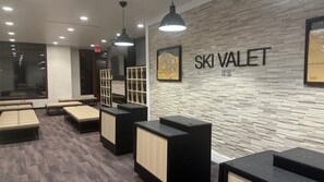 Un hall d’entrée moderne dans un complexe hôtelier de ski, avec des espaces de détente, un comptoir d’accueil et une enseigne fixée au mur indiquant « SKI VALLET ».