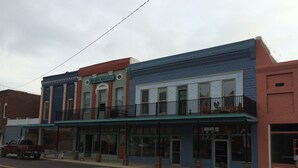A street view of a row of buildings with a blue storefront and a red truck parked on the street.