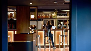 A bar area with a counter, stools, and a bartender.