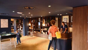 A lobby with a foosball table, wooden flooring, and a reception desk.