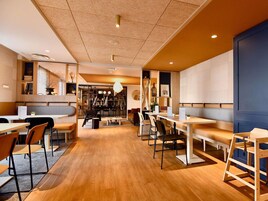 Un intérieur moderne avec un plancher en bois, des tables, des chaises et un espace détente doté de bancs.