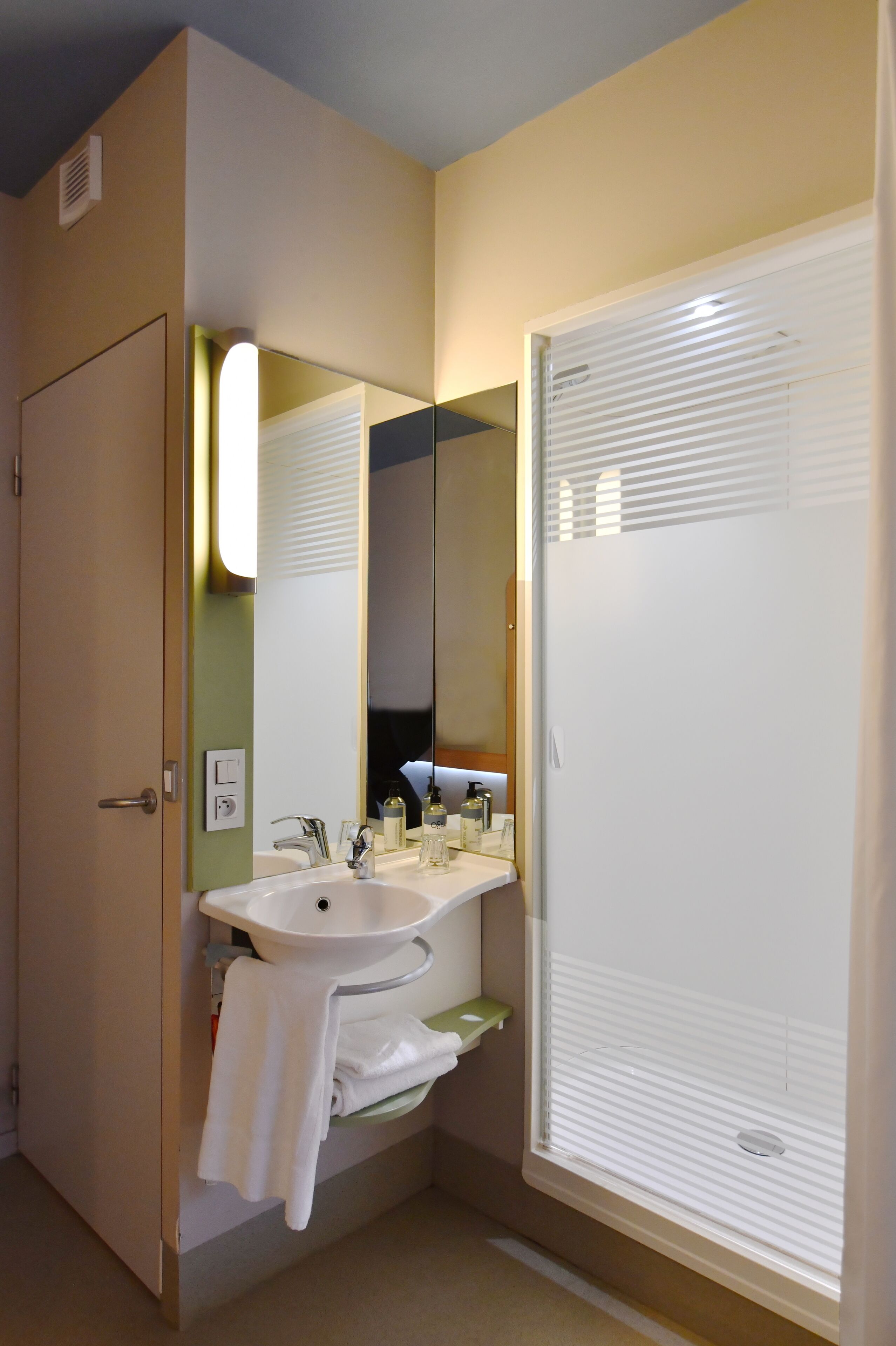 Un baño con lavamanos, espejo y perchero para toallas.