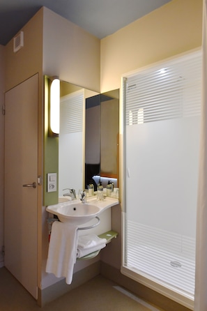 A bathroom with a sink, mirror, and towel rack. - ibis budget Nantes Rezé Aéroport (Reze)