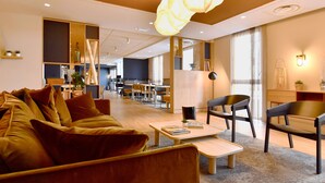 A modern lounge area with sofas, a coffee table, and a dining area with chairs and tables.