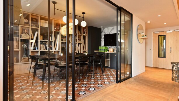 A modern interior with a dining area, kitchen, and a large sliding glass door leading to a balcony.