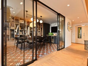 Un intérieur moderne comprenant un coin repas, une cuisine et une grande porte-fenêtre coulissante donnant sur un balcon.