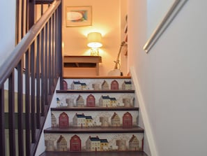 Un escalier avec des rampes en bois et une lampe fixée au mur.