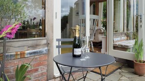 Une terrasse avec une table, une bouteille de champagne et deux verres.