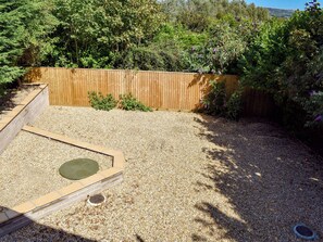 A backyard with a wooden fence, gravel ground, and a raised planter box. - 2 bedroom accommodation in Sandown (Sandown)