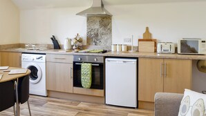 A modern kitchen with a washing machine, dishwasher, oven, and microwave. - 2 bedroom accommodation in Sandown (Sandown)