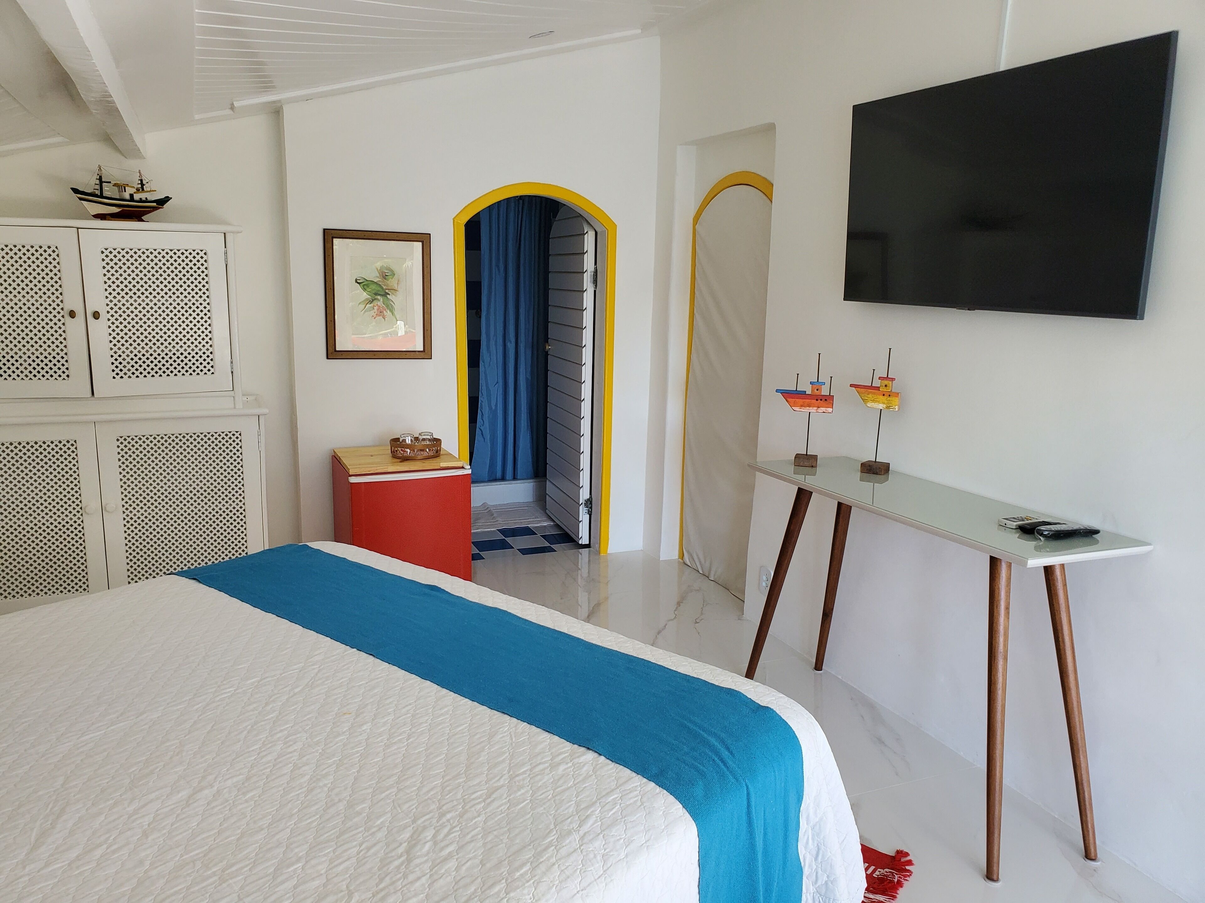 A bedroom with a bed, a desk, a TV, and a wardrobe.