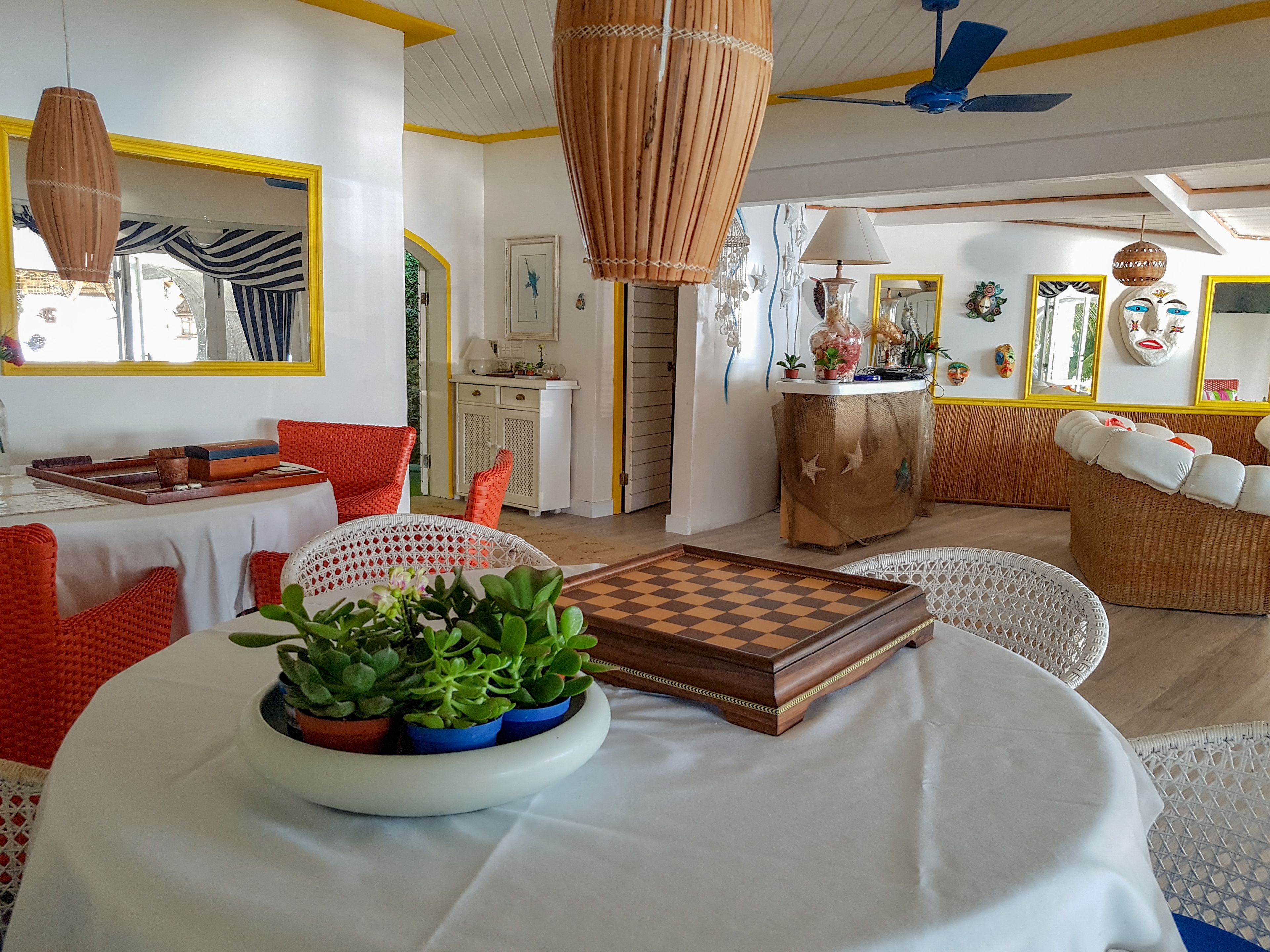 Una sala de estar acogedora con un tablero de ajedrez, un comedor con una mesa preparada para dos personas y una pared de color amarillo brillante.