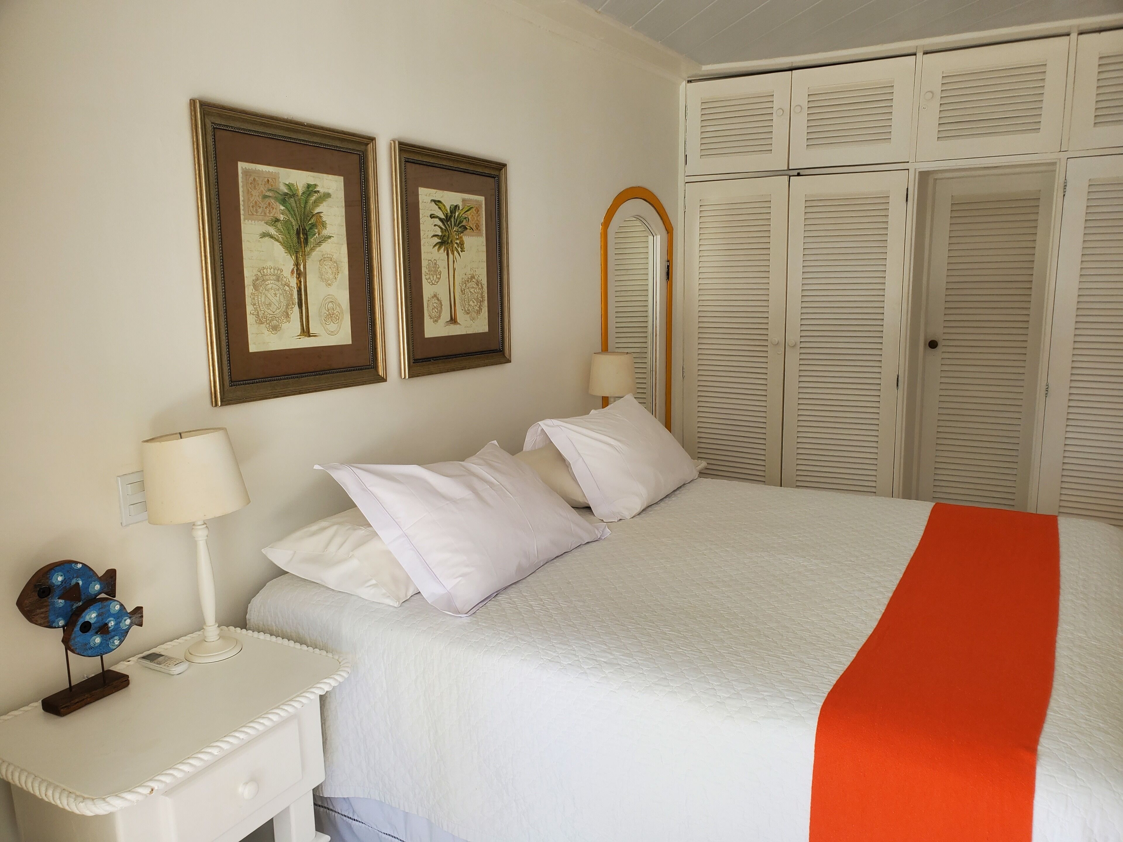 A neatly arranged bedroom with a bed, bedside tables, lamps, and a wardrobe.