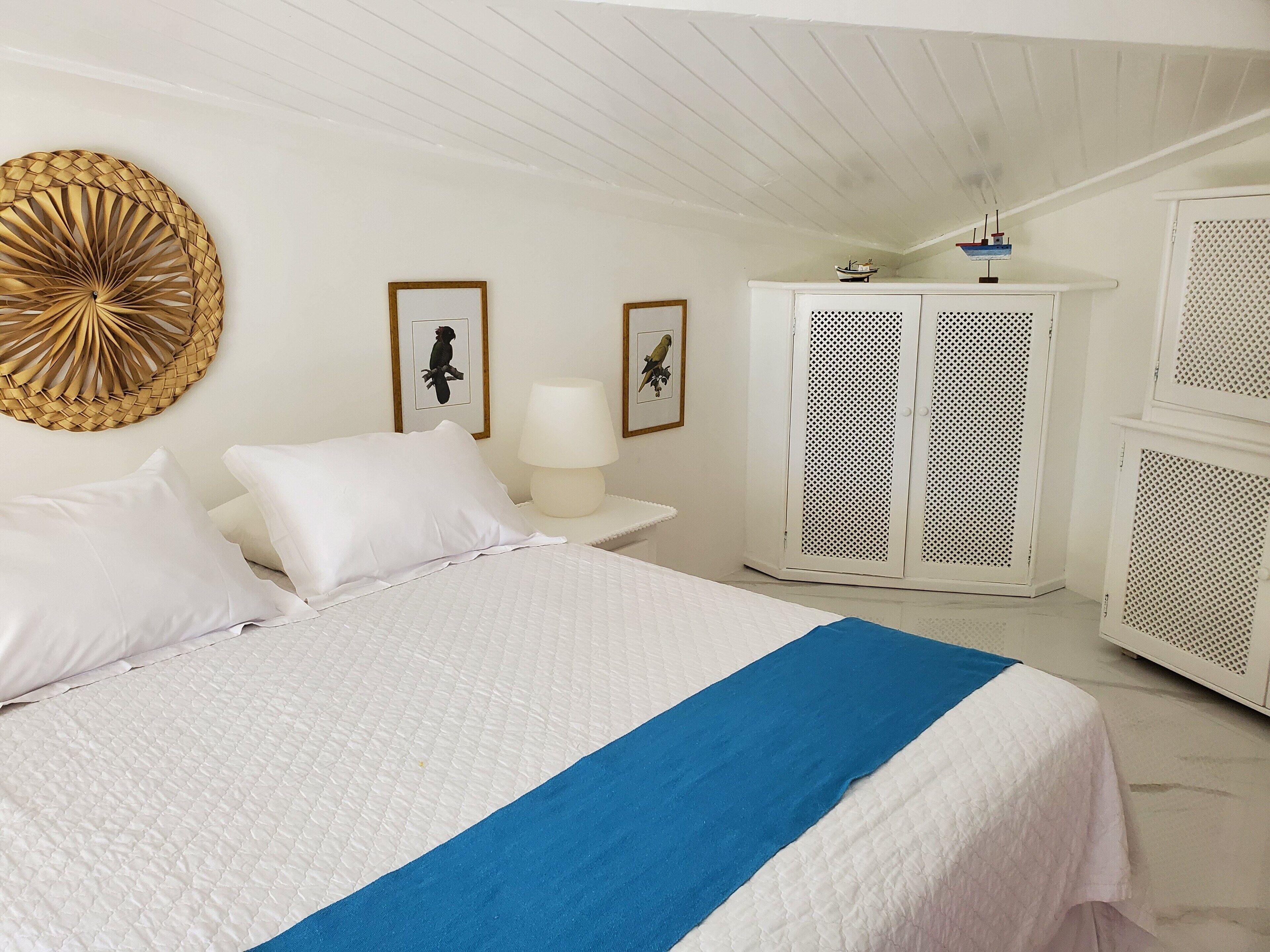 A neatly arranged bedroom with a bed, a bedside table, a lamp, and a wardrobe.