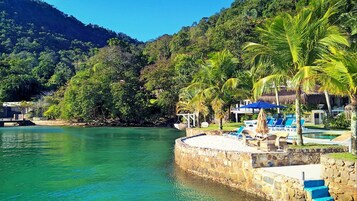 Praia particular, areia branca, guarda-sóis, toalhas de praia 