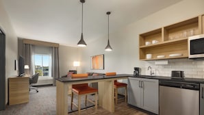 Una cocina moderna con una isla central, taburetes de bar, microondas y lavavajillas.
