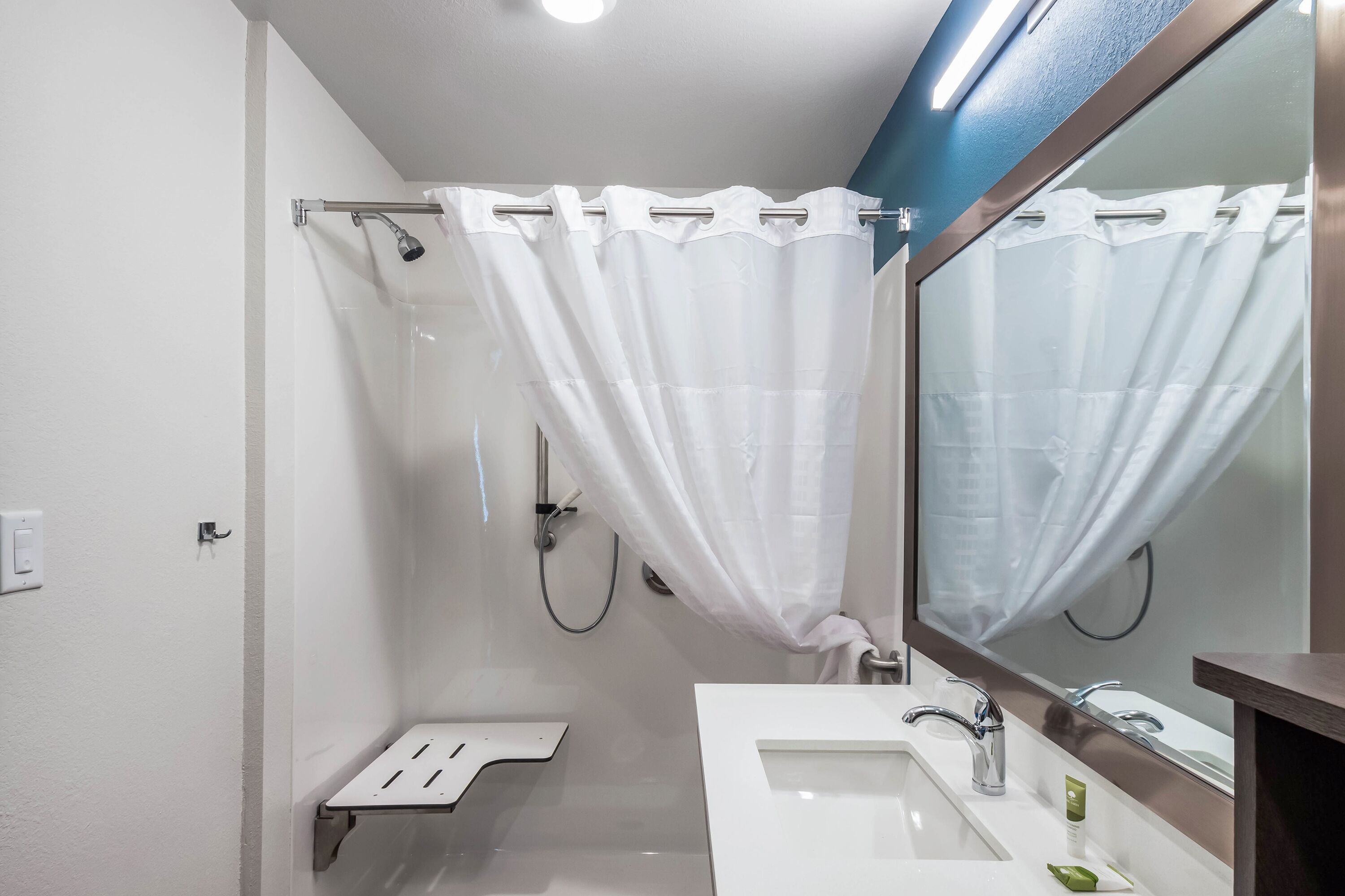 A modern bathroom with a shower, a sink, and a large mirror.