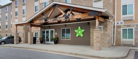 A multi-story hotel with a brick facade, a covered entrance, and a green star-shaped sign.