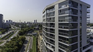 Un moderno edificio de varios pisos con balcones, rodeado por un paisaje urbano y calles.