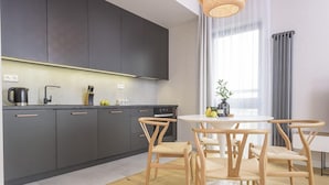 Una cocina moderna con armarios oscuros, una mesa redonda y sillas de madera.