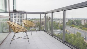 Un balcón con dos sillas de mimbre y vista a un paisaje urbano.
