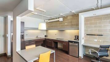 A modern kitchen with a dining area, featuring a built-in oven, microwave, and dishwasher.