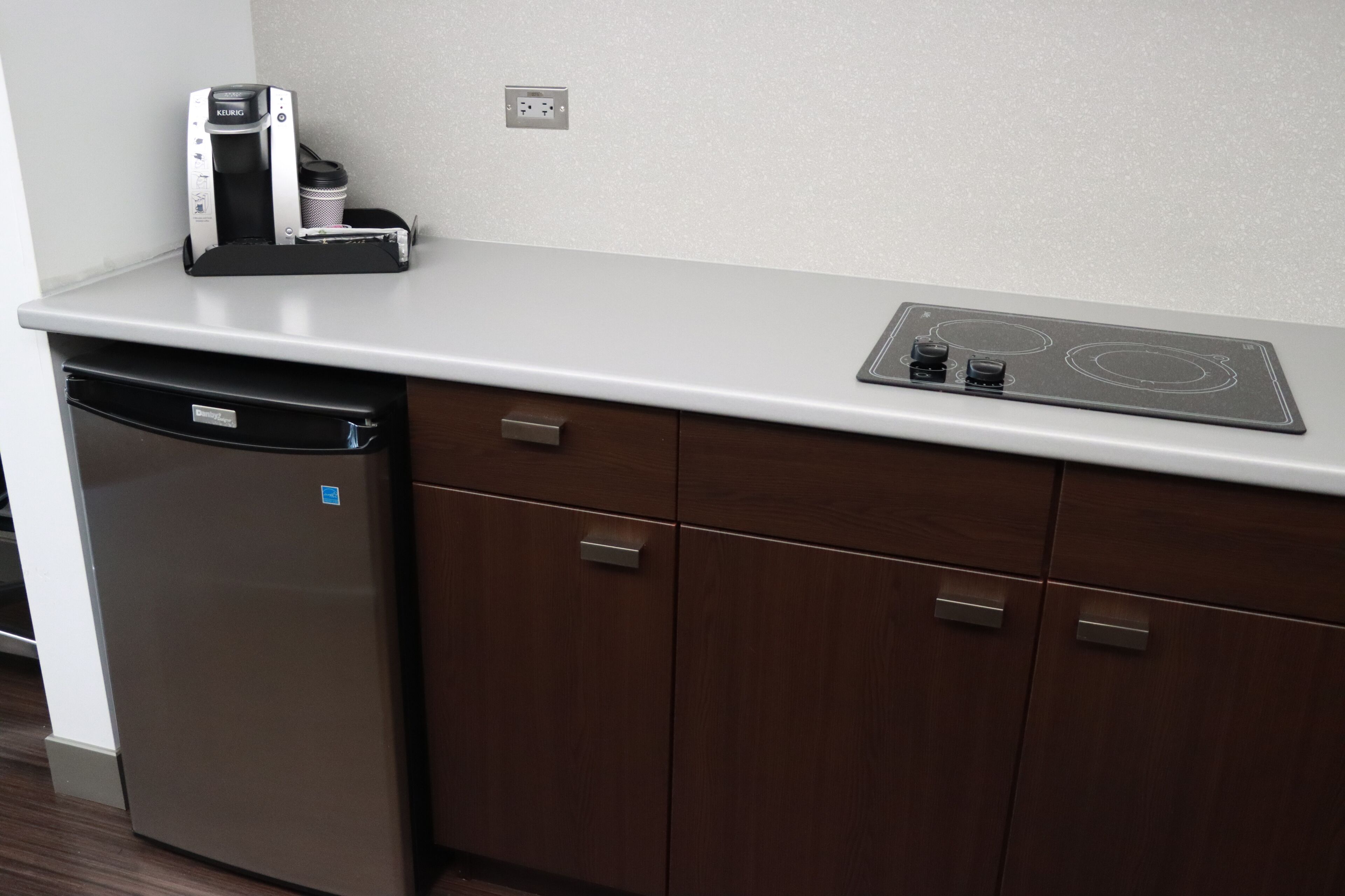 A kitchen with a dishwasher, a coffee maker, and a built-in stovetop.