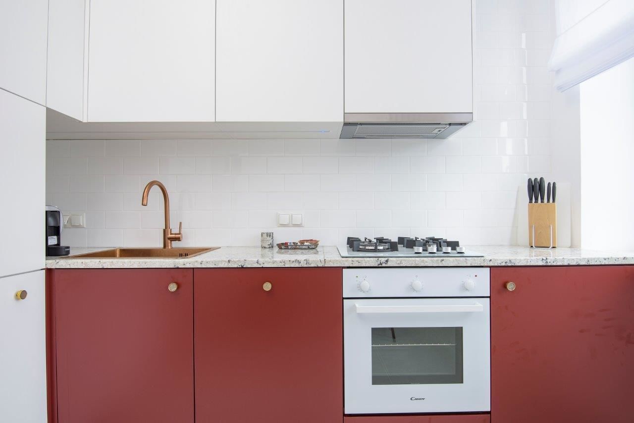 A kitchen with white cabinets, a copper faucet, a gas stove, and a built-in oven.