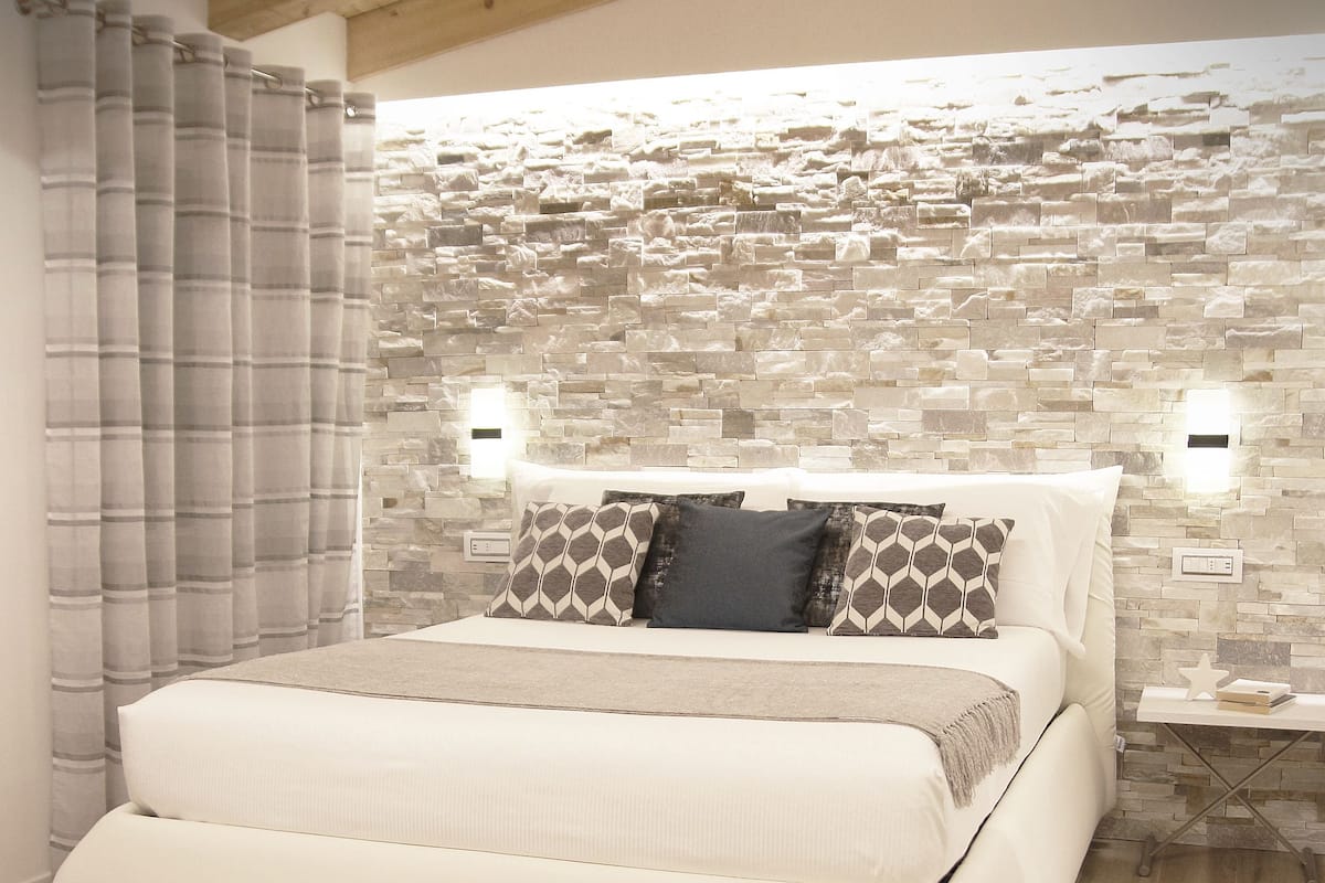 Un dormitorio moderno con una cama grande, una pared de piedra y un techo de madera.