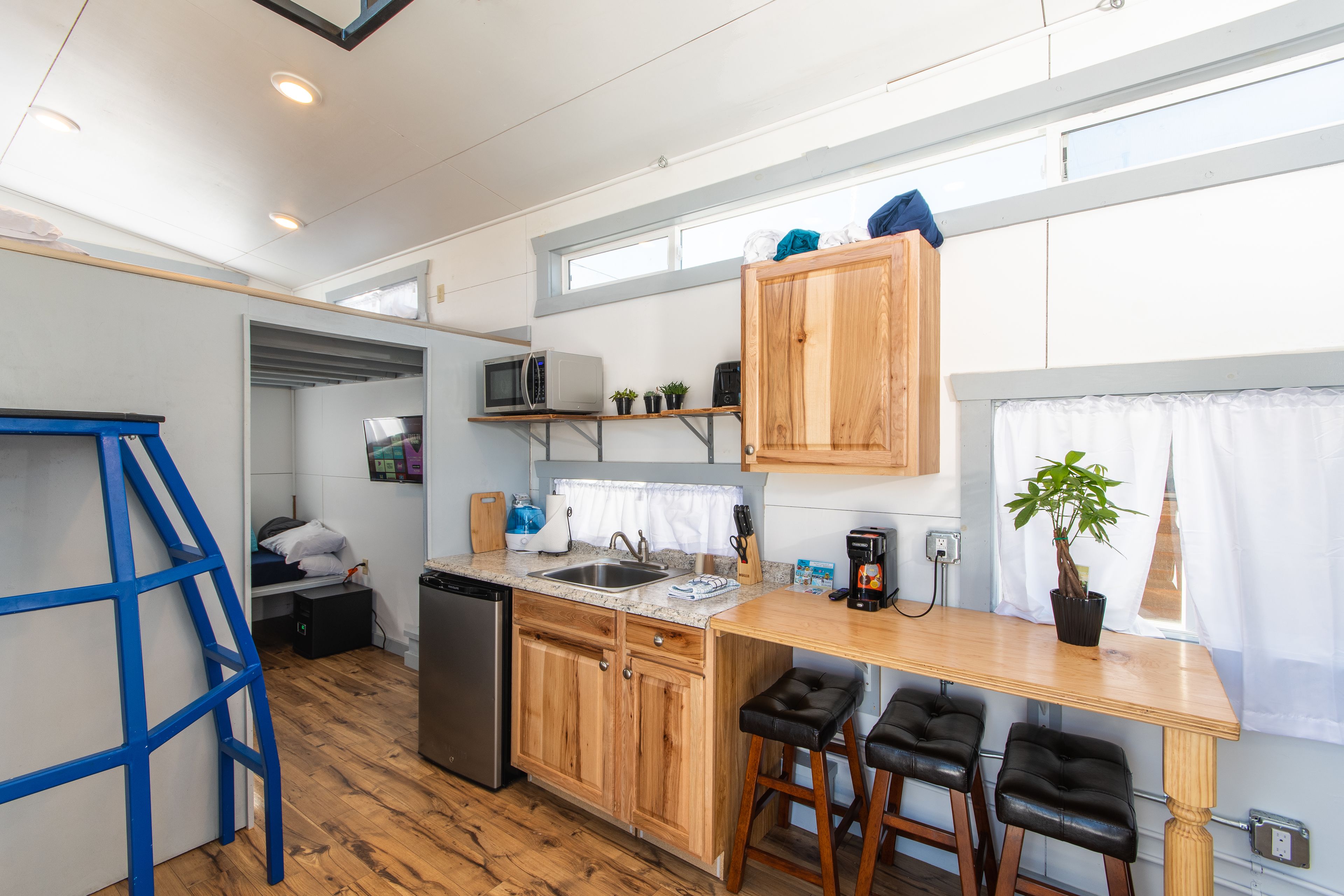 Une cuisine compacte avec des meubles en bois, un four à micro-ondes encastré et un petit îlot central avec des tabourets.