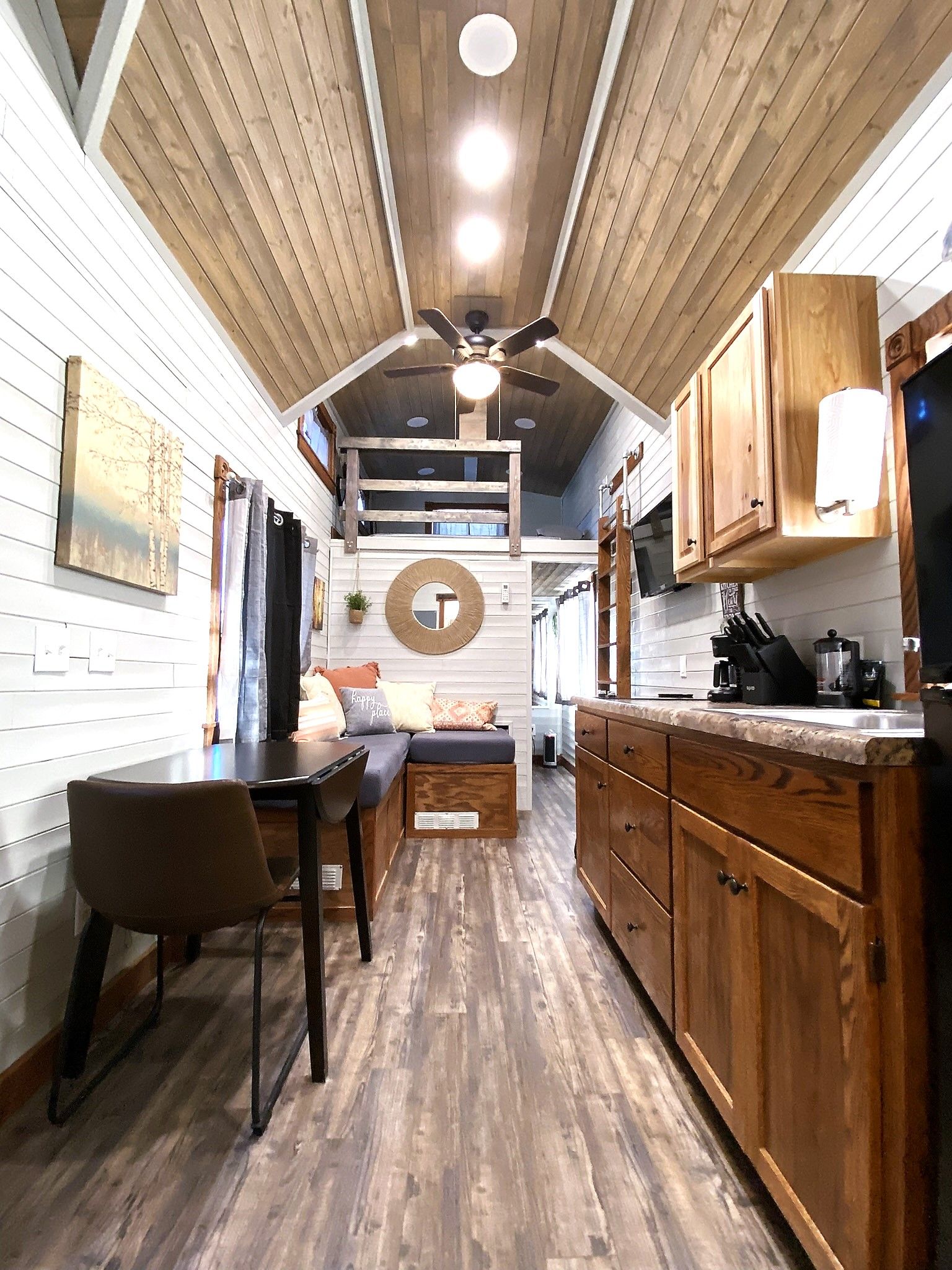 A kitchen with wooden cabinets, a dining area with a table and chairs, and a ceiling fan.