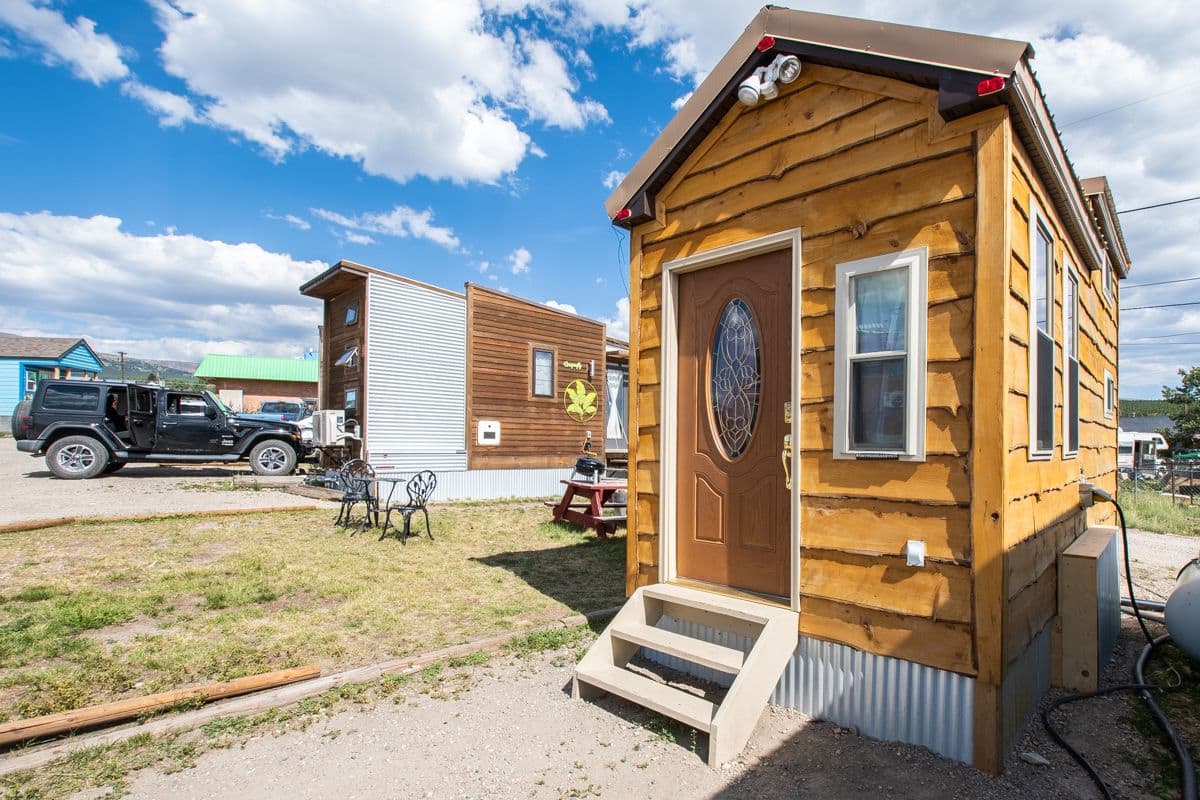 Une petite cabane en bois avec une porte d’entrée et des marches menant à celle-ci.