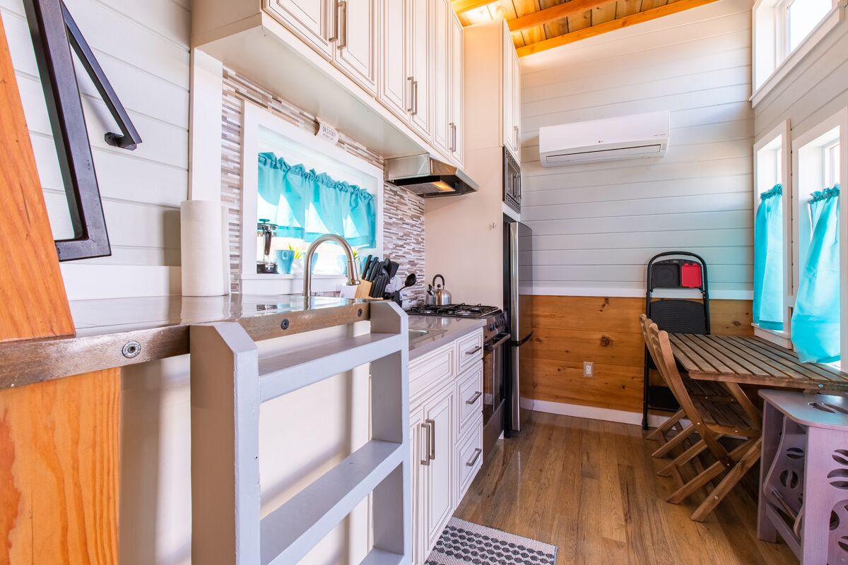 A compact kitchen with white cabinetry, a wooden countertop, and a small dining area with a table and chairs.