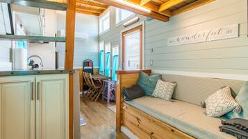 Interior acogedor de una cabaña con un banco de madera, una zona de cocina y un letrero en la pared que dice “WHAT A WONDERFUL LIFE”.