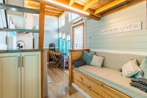 Interior acogedor de una cabaña con un banco de madera, una zona de cocina y un letrero en la pared que dice “WHAT A WONDERFUL LIFE”.