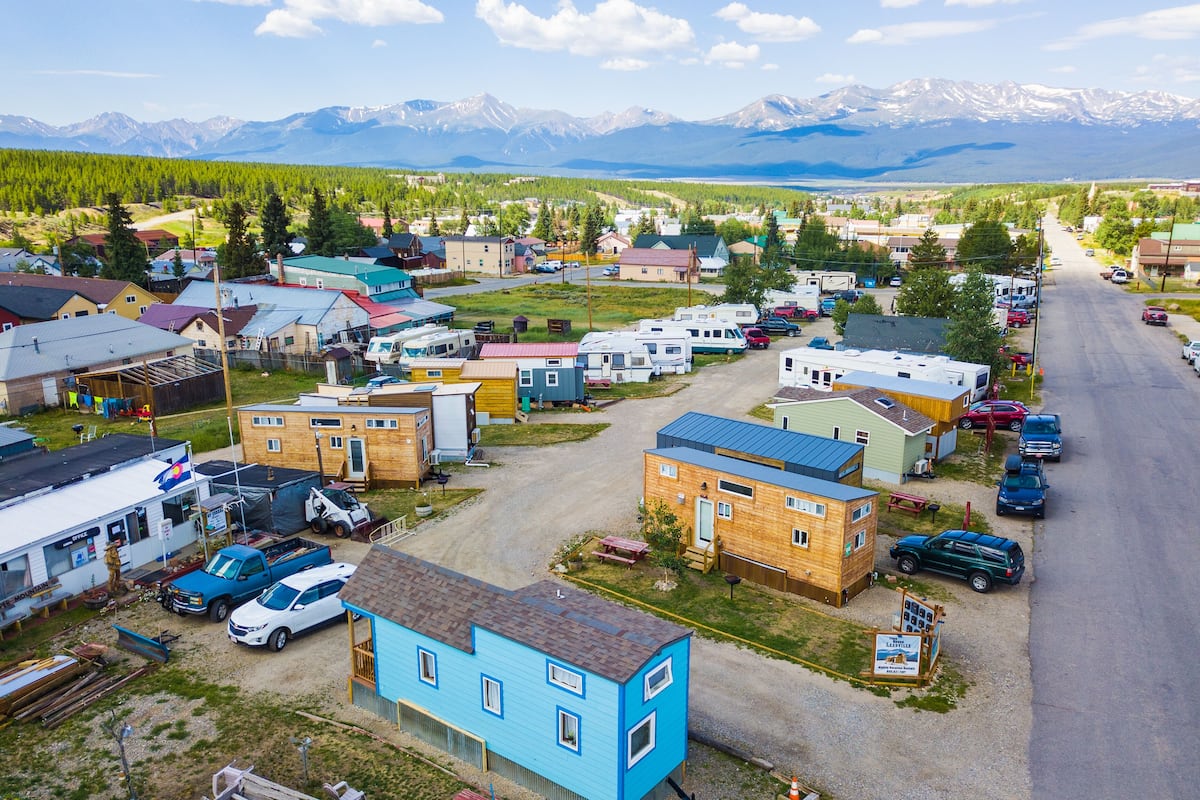 Une petite ville où l'on peut voir des camping-cars et des voitures garés le long de la rue, le tout étant entouré de montagnes.