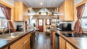 Une cuisine de taille réduite, dotée de meubles en bois, d’un évier, d’un four à micro-ondes et d’une cuisinière.