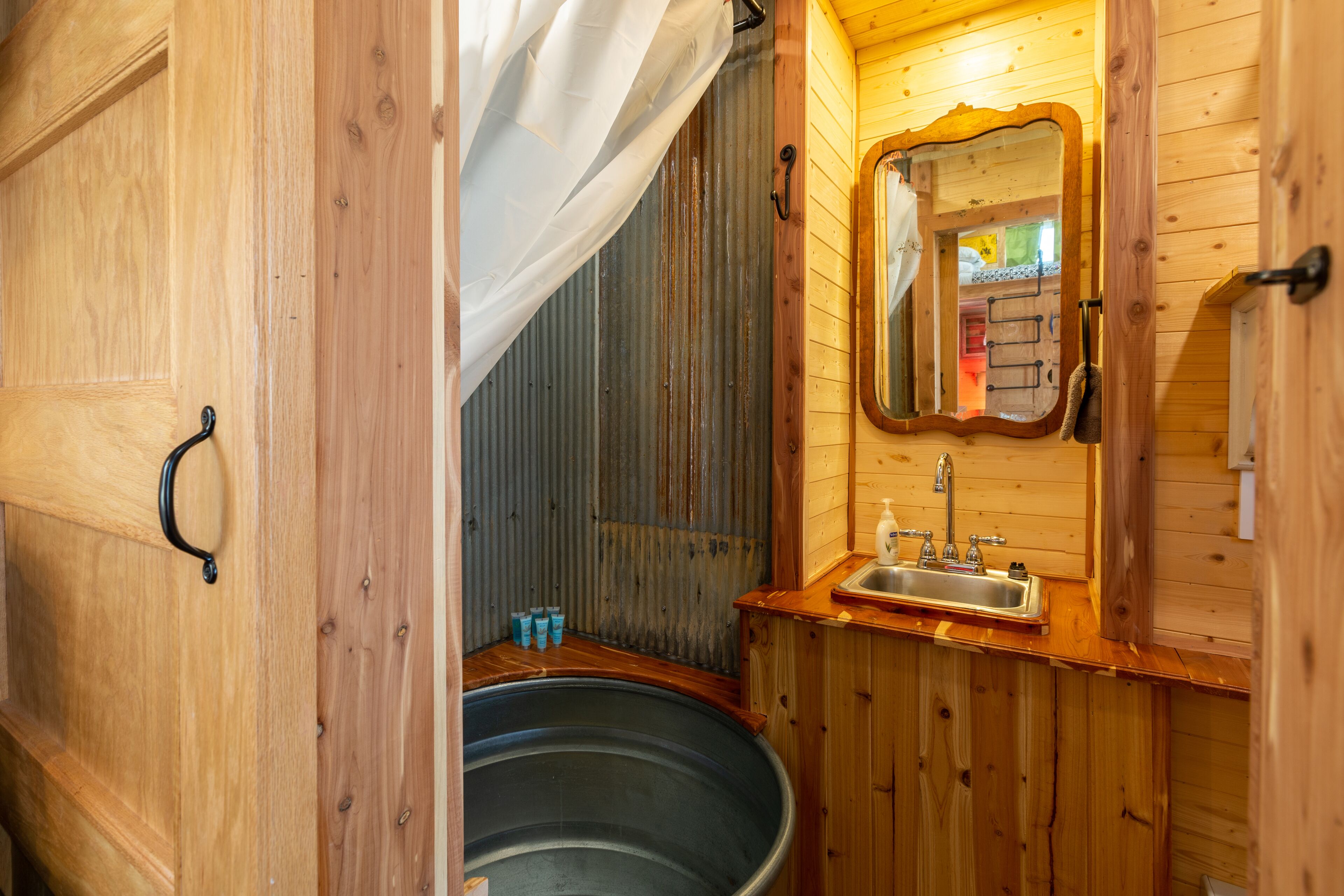 A wooden cabin bathroom with a large bathtub, a sink, and a mirror.