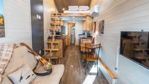 Un intérieur de chalet chaleureux avec un lit en mezzanine, des meubles en bois, un coin repas et un téléviseur.