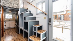 Une cuisine moderne dotée d’un réfrigérateur encastré, d’un plancher en bois et d’un escalier avec des étagères ouvertes.