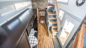 Une cuisine compacte avec un plancher en bois, un évier encastré et un petit coin repas agrémenté d’un banc.