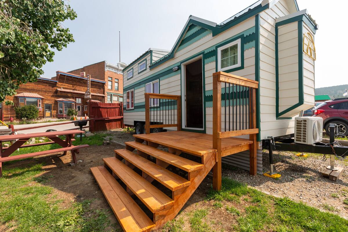 Une maison mobile dotée d’une terrasse en bois et d’un escalier menant à l’entrée.