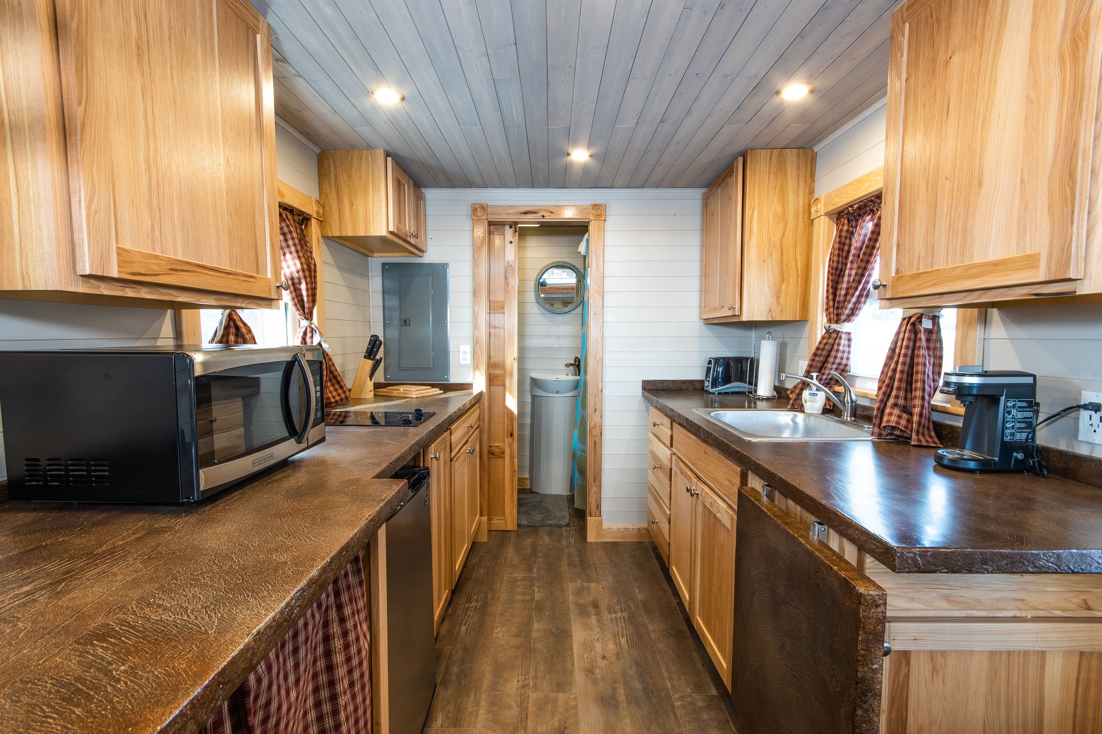 A compact kitchen with wooden cabinets, a microwave, a coffee maker, and a sink.